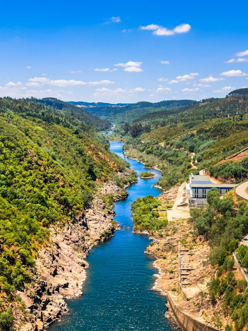 River winding through a forested gorge past a small dam