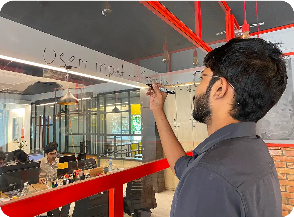 6sense engineer mapping a system flow on a glass whiteboard