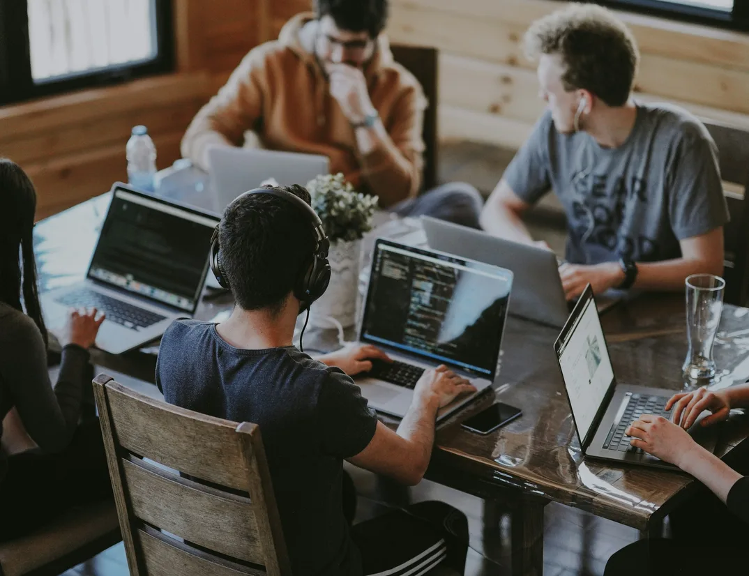 Engineers working on laptops around a shared wooden table