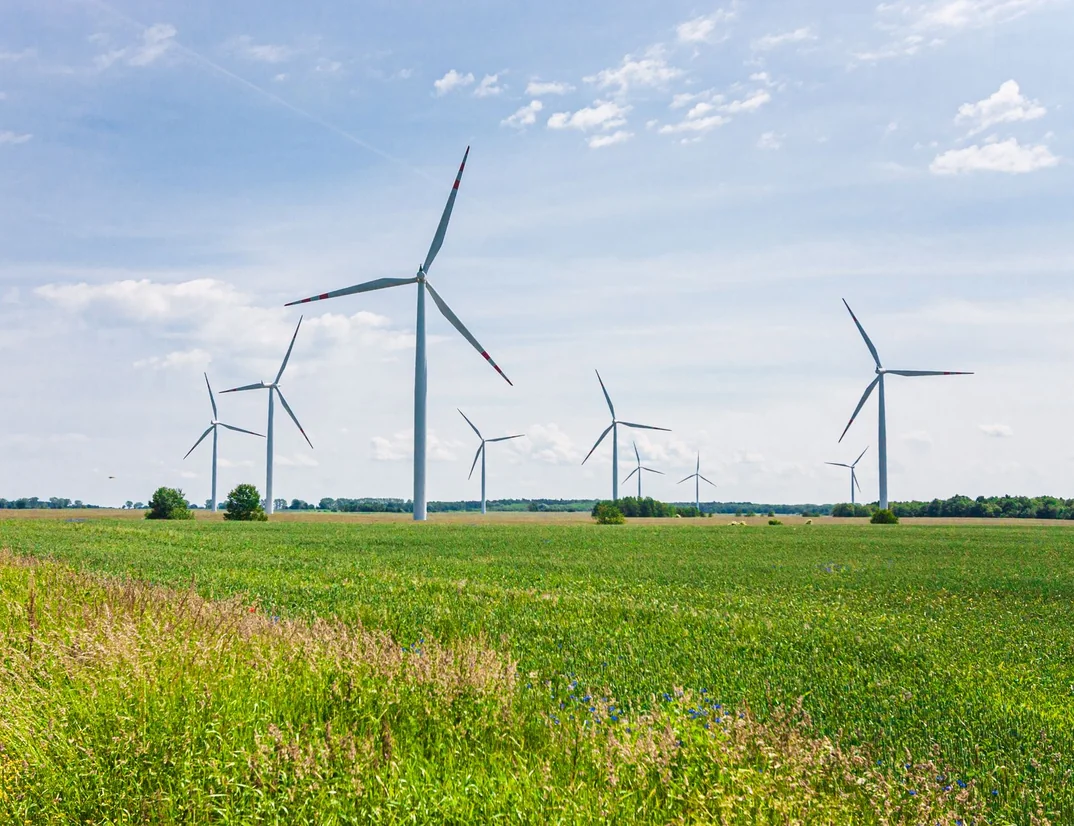 Wind turbines standing over a green field under a blue sky