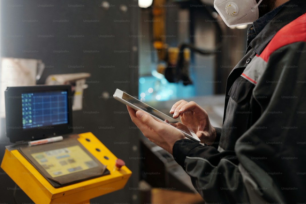 Engineer holding a tablet beside industrial equipment